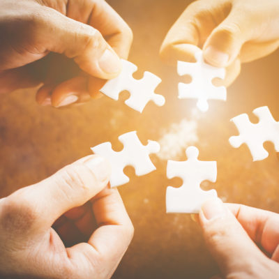 Hand of diverse people connecting jigsaw puzzle. Concept of partnership and teamwork in business