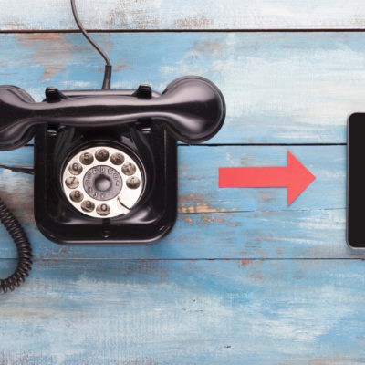 Old telephone and mobile phone on a blue wooden board